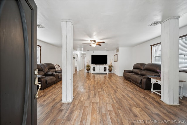living area with wood finished floors, visible vents, and a ceiling fan