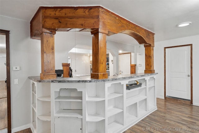 kitchen with baseboards, stone countertops, wood finished floors, and open shelves