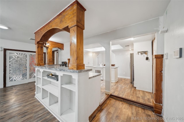 kitchen featuring wood finished floors, light stone counters, open shelves, visible vents, and white electric range oven