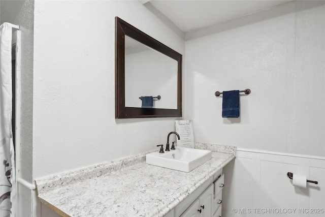 full bathroom with a wainscoted wall and vanity