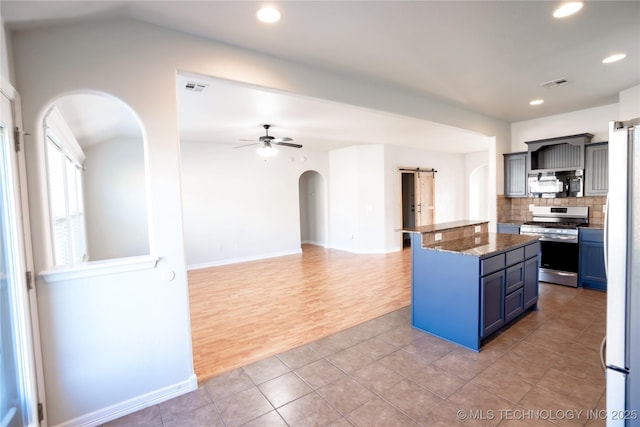 kitchen featuring visible vents, arched walkways, blue cabinets, a ceiling fan, and appliances with stainless steel finishes