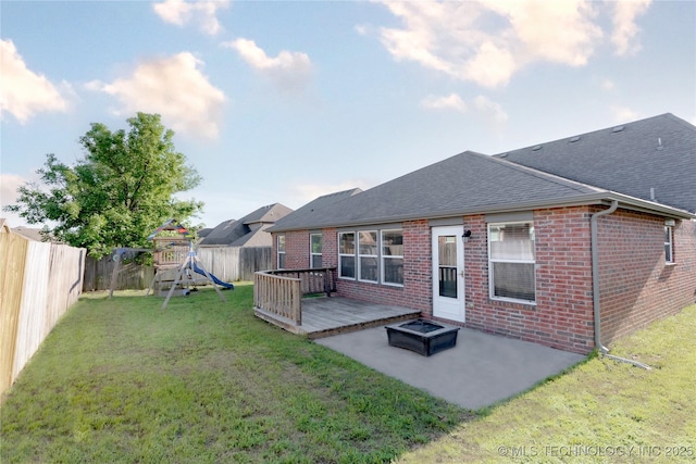 back of house featuring roof with shingles, brick siding, a fenced backyard, a playground, and a patio