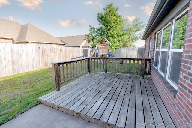 wooden deck with a lawn, a fenced backyard, and a playground
