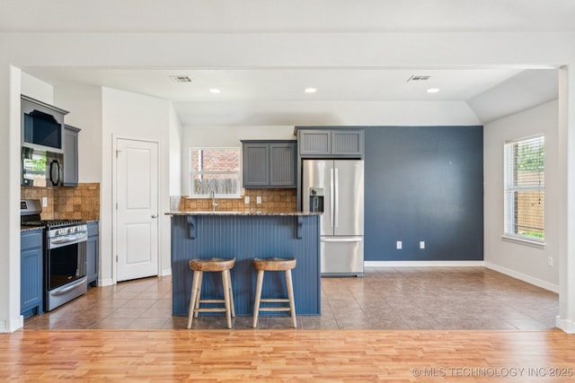 13323 S 21st St, Bixby, OK 74008 - kitchen with appliances with stainless steel finishes, a breakfast bar area, light tile patterned floors, tasteful backsplash, and a center island