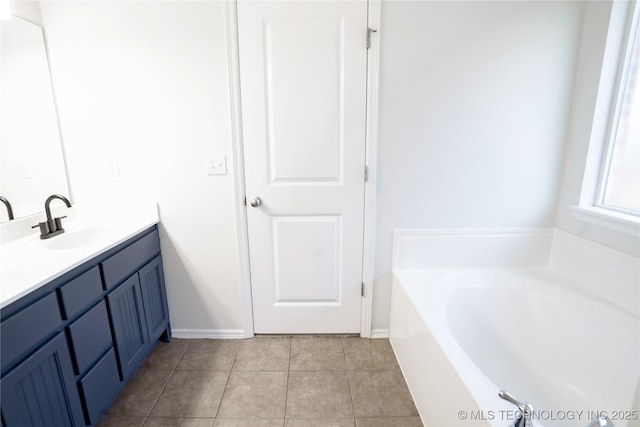 bathroom featuring tile patterned floors, baseboards, a garden tub, and vanity