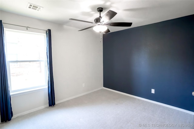 carpeted empty room with visible vents, baseboards, ceiling fan, and a wealth of natural light