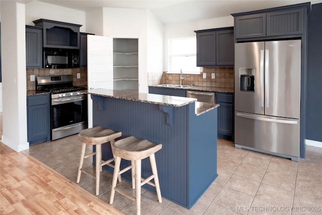 13323 S 21st St, Bixby, OK 74008 - kitchen featuring stainless steel appliances, a sink, dark stone countertops, a center island, and decorative backsplash