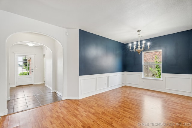13323 S 21st St, Bixby, OK 74008 - empty room with arched walkways, wood finished floors, a chandelier, and wainscoting