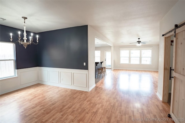 13323 S 21st St, Bixby, OK 74008 - spare room with a barn door, light wood finished floors, a chandelier, a ceiling fan, and a wainscoted wall