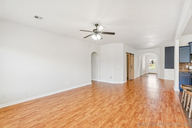 13323 S 21st St, Bixby, OK 74008 - unfurnished living room with arched walkways, light wood finished floors, and a ceiling fan
