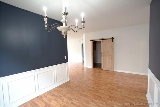 13323 S 21st St, Bixby, OK 74008 - spare room with a chandelier, light wood finished floors, a barn door, wainscoting, and a decorative wall