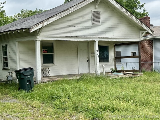 rear view of property with a porch and a lawn