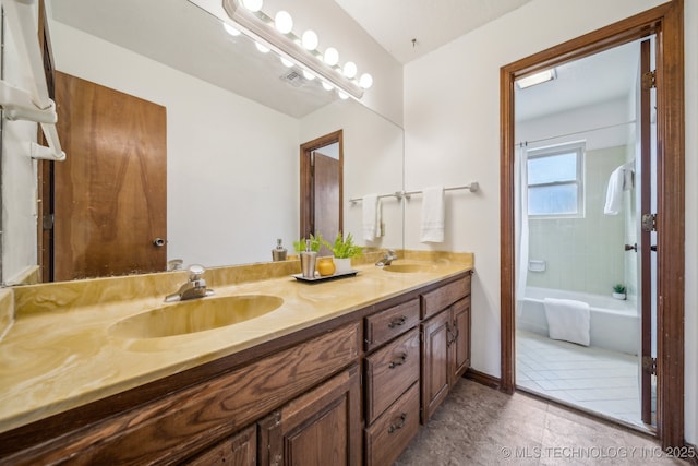 bathroom with double vanity, a sink, tile patterned floors, and baseboards