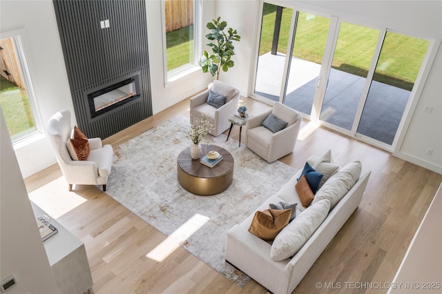 living area with a glass covered fireplace, wood finished floors, and baseboards