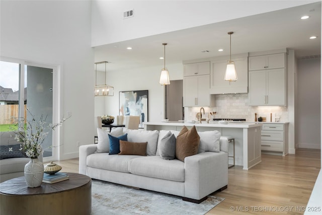 living area featuring visible vents, recessed lighting, light wood finished floors, and baseboards