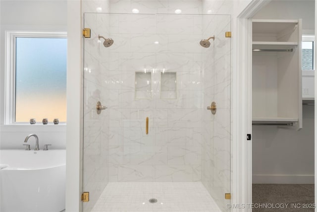 bathroom featuring a freestanding tub, a shower stall, and a walk in closet