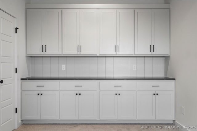 kitchen featuring white cabinetry, baseboards, dark countertops, and decorative backsplash