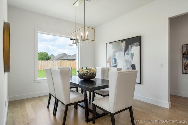 dining area featuring baseboards, light wood-type flooring, visible vents, and an inviting chandelier