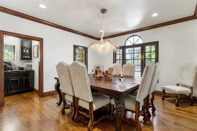 dining area featuring crown molding, baseboards, a notable chandelier, and light wood-style floors