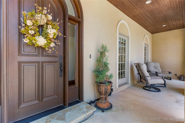 doorway to property with a porch and stucco siding
