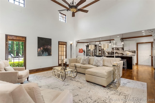 living room featuring ceiling fan, dark wood-style floors, baseboards, and a towering ceiling