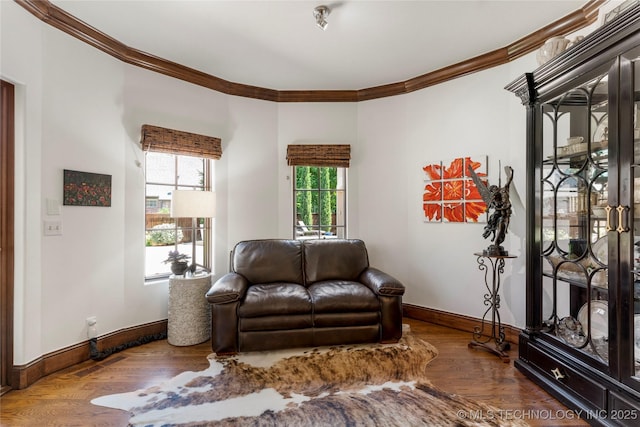living area with baseboards, ornamental molding, and wood finished floors