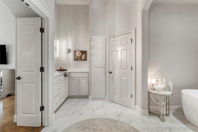 bathroom featuring a freestanding tub, baseboards, vanity, and marble finish floor