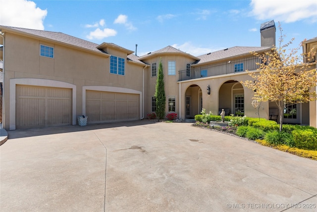 mediterranean / spanish home featuring a balcony, stucco siding, driveway, and a chimney