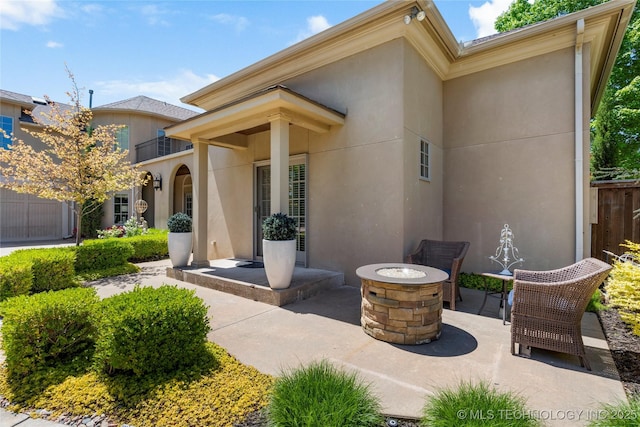 exterior space with a fire pit, a balcony, a patio area, and stucco siding