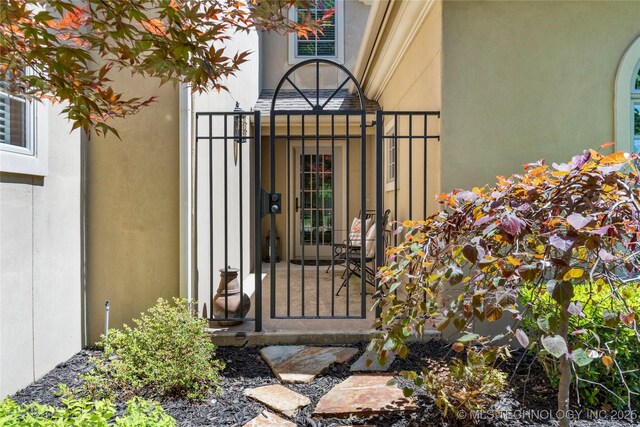 property entrance featuring a gate and stucco siding