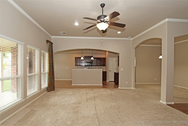 unfurnished living room featuring visible vents, crown molding, a ceiling fan, and arched walkways