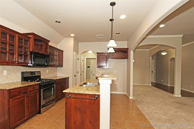 kitchen featuring black microwave, stainless steel gas range, arched walkways, and a sink