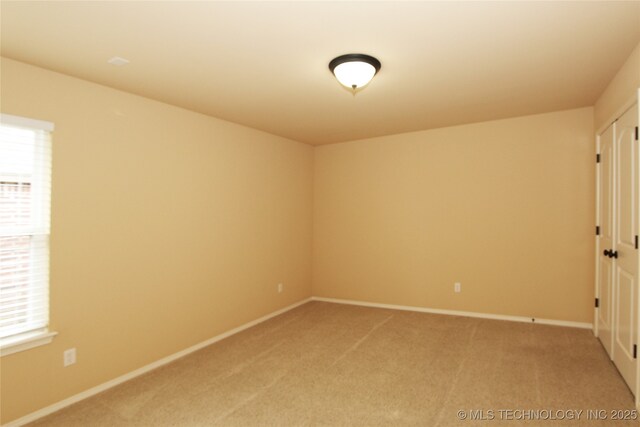 unfurnished room featuring light carpet and baseboards