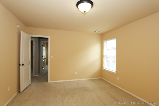 spare room featuring baseboards, visible vents, and light colored carpet