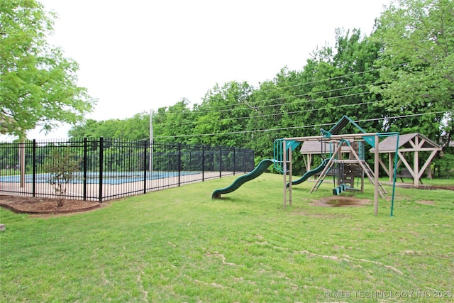 communal playground featuring fence, a yard, and a community pool