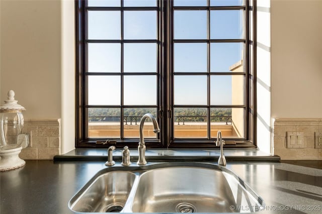 details featuring dark countertops, decorative backsplash, and a sink