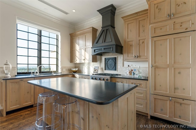 kitchen with a sink, light brown cabinets, dark wood finished floors, premium range hood, and a kitchen island
