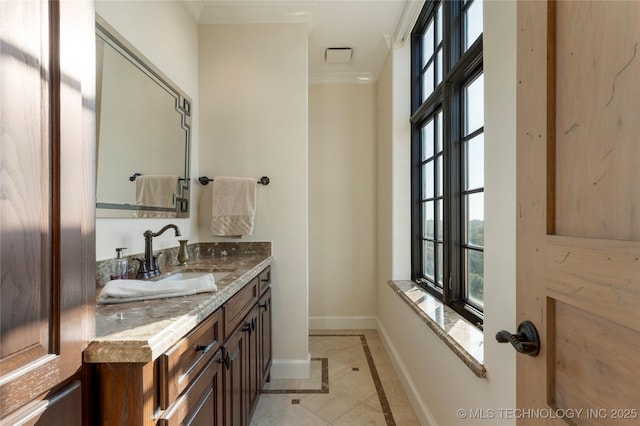 bathroom with crown molding, baseboards, plenty of natural light, and vanity