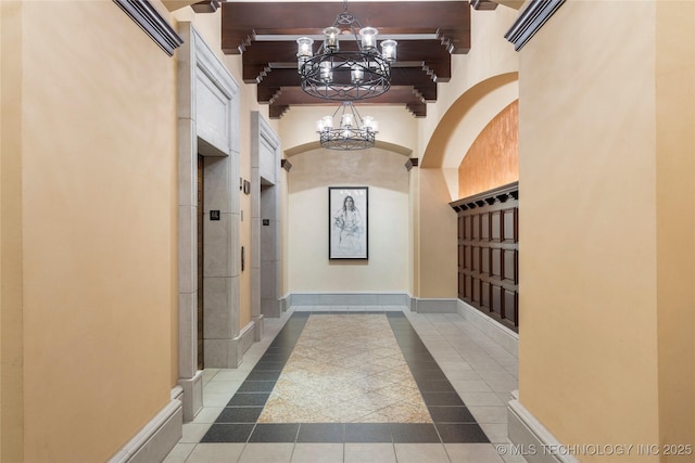 hall featuring tile patterned floors, baseboards, beam ceiling, and a notable chandelier