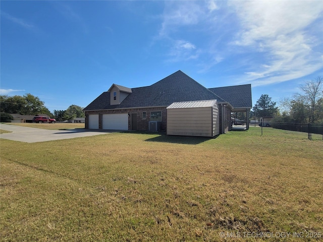 view of side of home with driveway, roof with shingles, a lawn, central AC unit, and fence