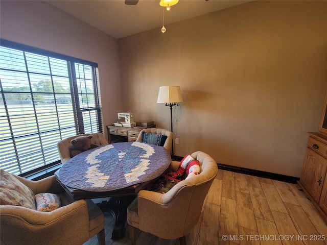 dining area featuring baseboards, a ceiling fan, and light wood-style flooring