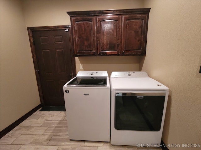 clothes washing area with baseboards, cabinet space, and washer and dryer
