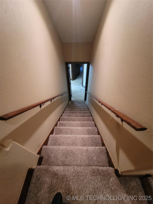 stairs featuring carpet floors and a textured wall
