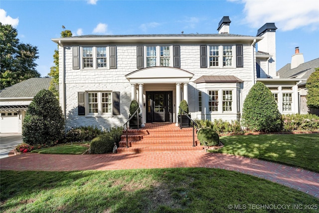 colonial inspired home featuring a chimney and a front yard