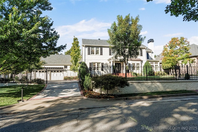view of front of property featuring a gate, a fenced front yard, a chimney, and driveway