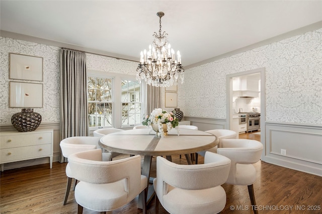 dining area with wallpapered walls, an inviting chandelier, wainscoting, and wood finished floors