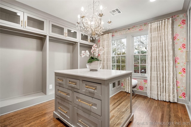 walk in closet with a notable chandelier, dark wood-style flooring, and visible vents