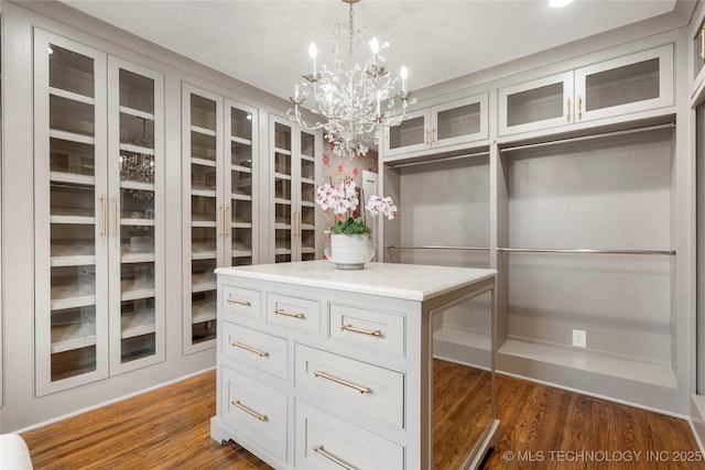 spacious closet featuring dark wood finished floors and a chandelier