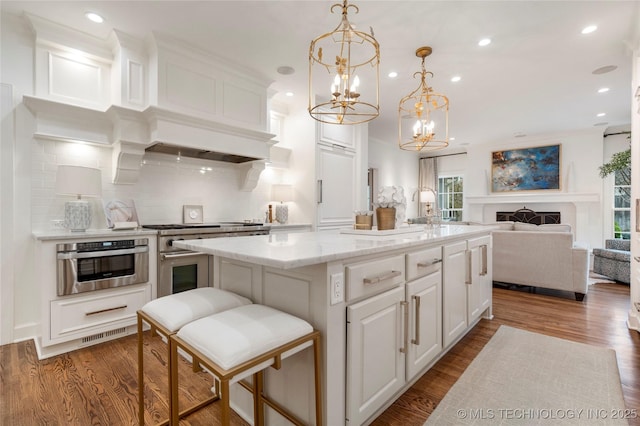 kitchen with a center island, tasteful backsplash, a chandelier, stainless steel appliances, and white cabinetry