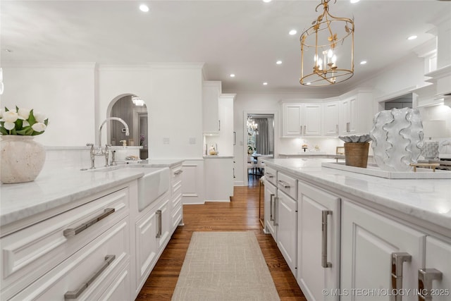 kitchen featuring light stone countertops, a sink, ornamental molding, recessed lighting, and white cabinetry